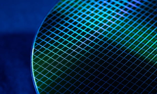 A silicon wafer lit with blue light on a blue gradient background