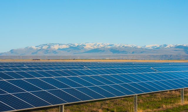 Solar panels in field surrounded by mountains
