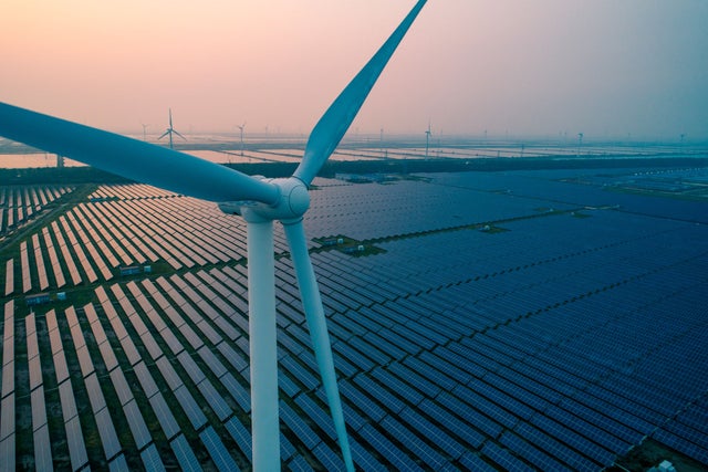 A wind turbine in front of solar panels